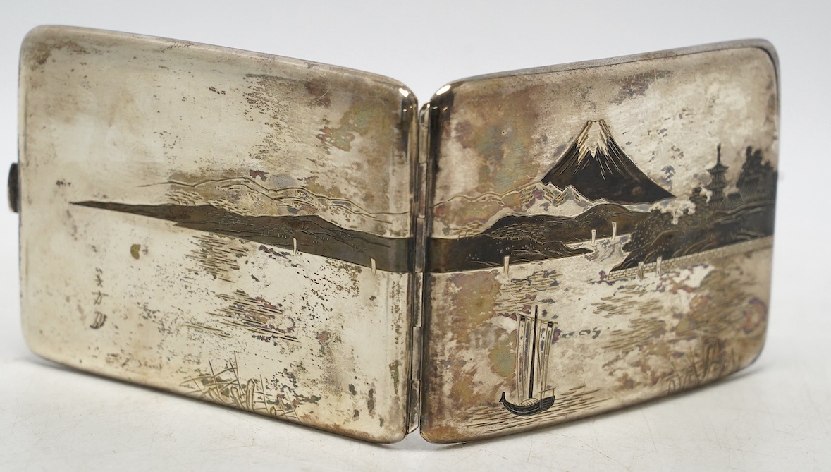 A white metal (stamped) and dark patinated Japanese silver cigarette case, decorated with a view of Mount Fuji, signed, 11cm, gross weight 113 grams. Condition - fair